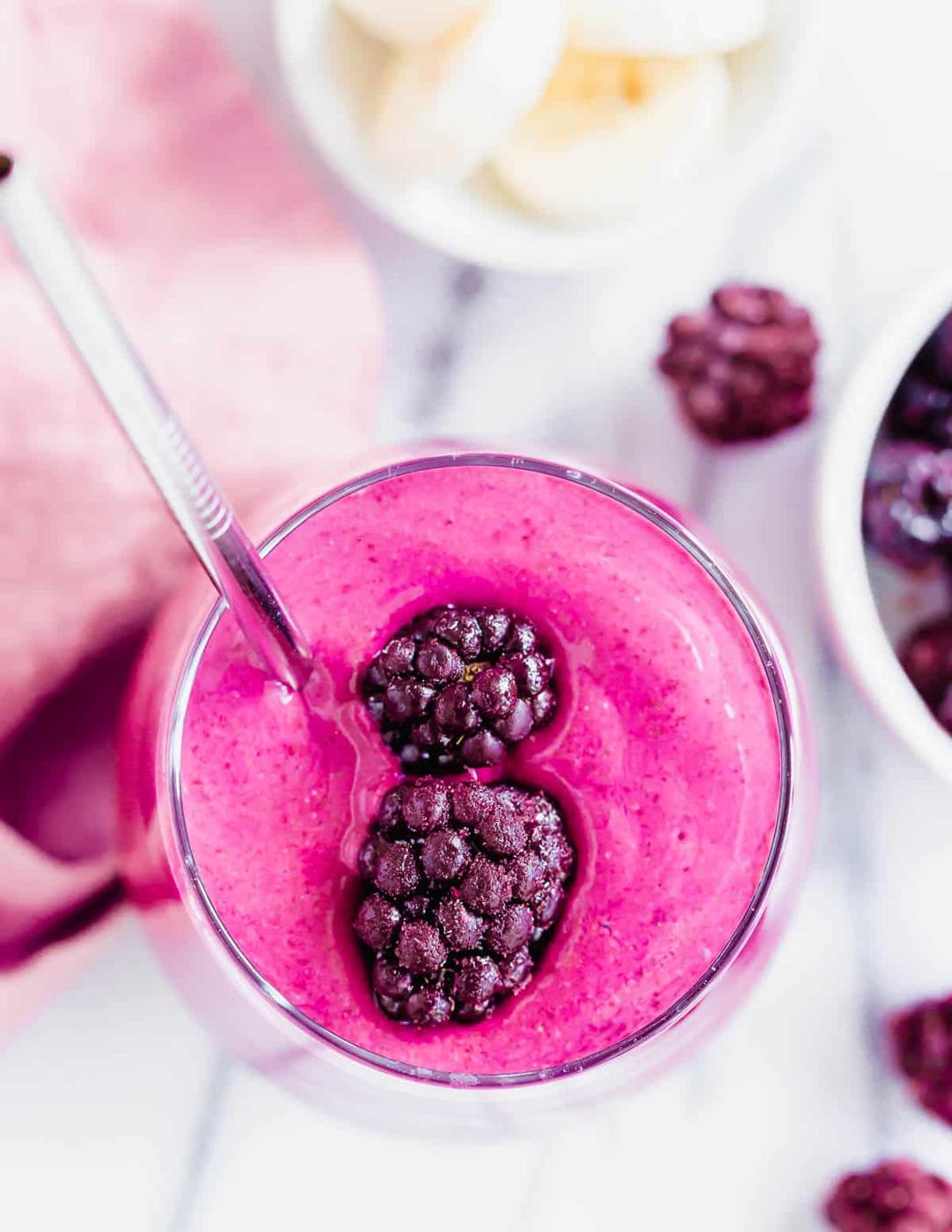 A pink smoothie with blackberries and bananas.