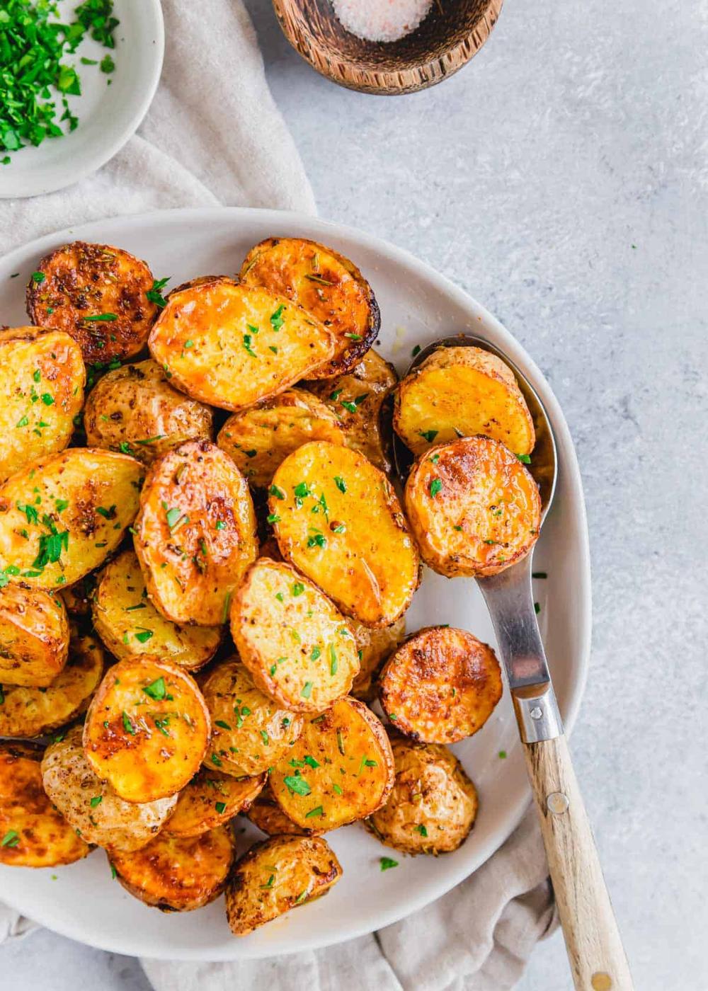 Baby potatoes cooked in an air fryer served on a plate with a spoon.