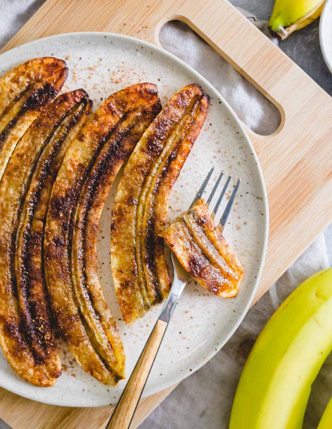 Caramelized air fried bananas on a plate with a fork.
