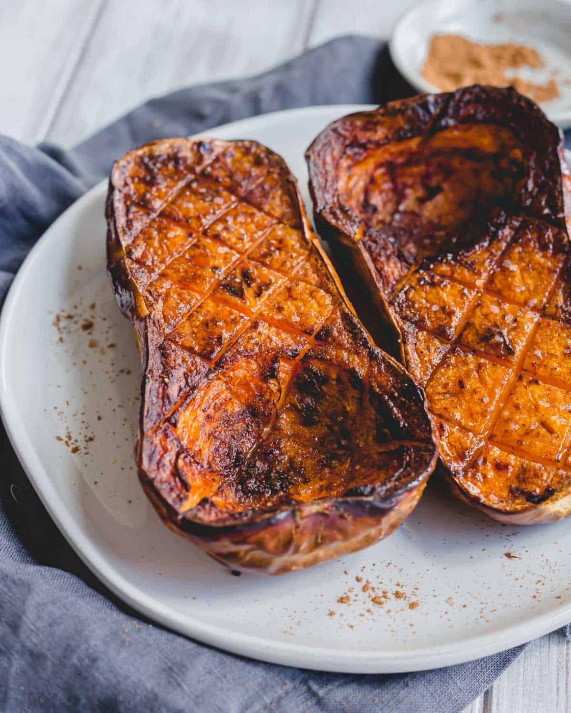 Caramelized air fryer butternut squash halves on a plate.