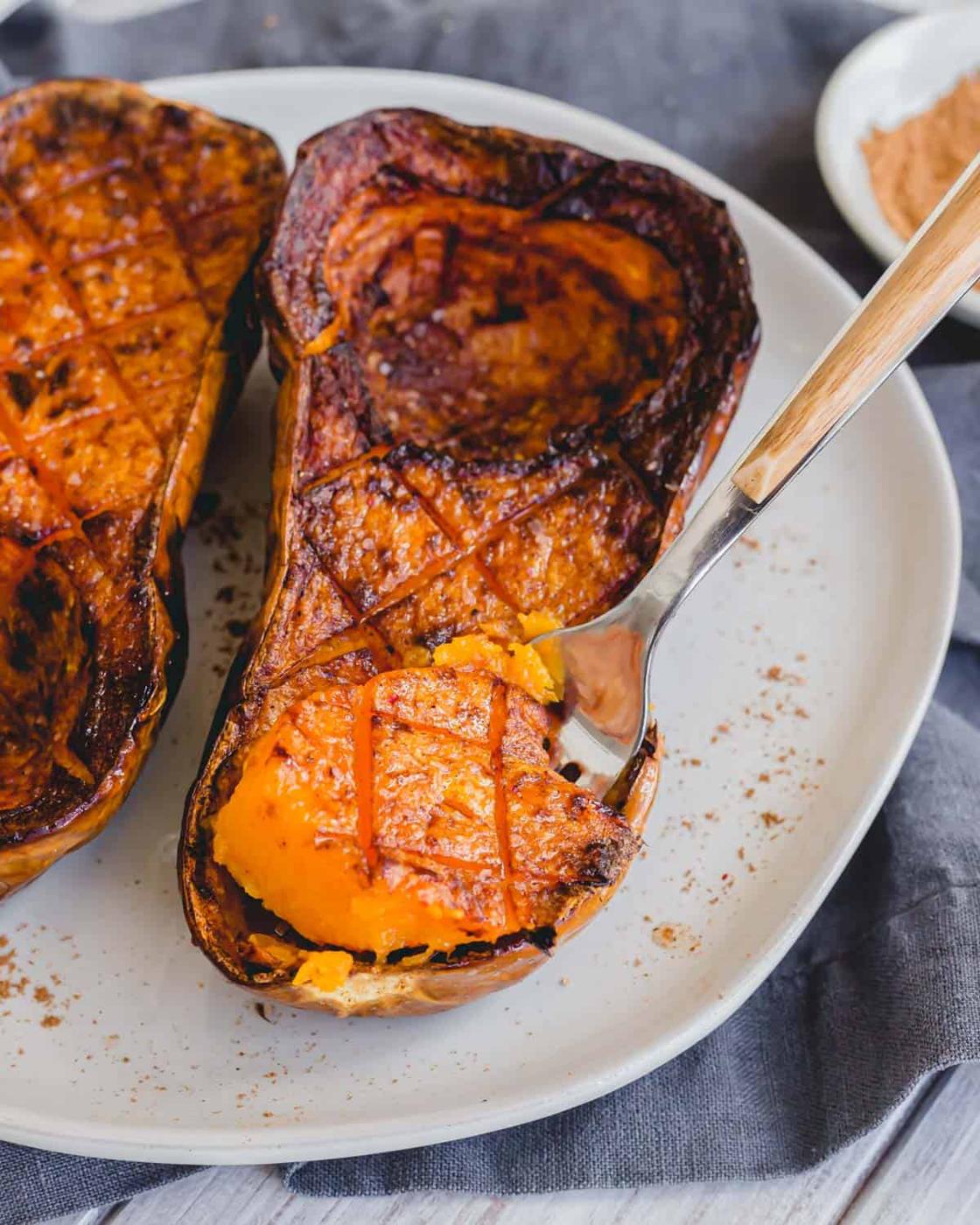 A fork scooping out air fried butternut squash on a plate.