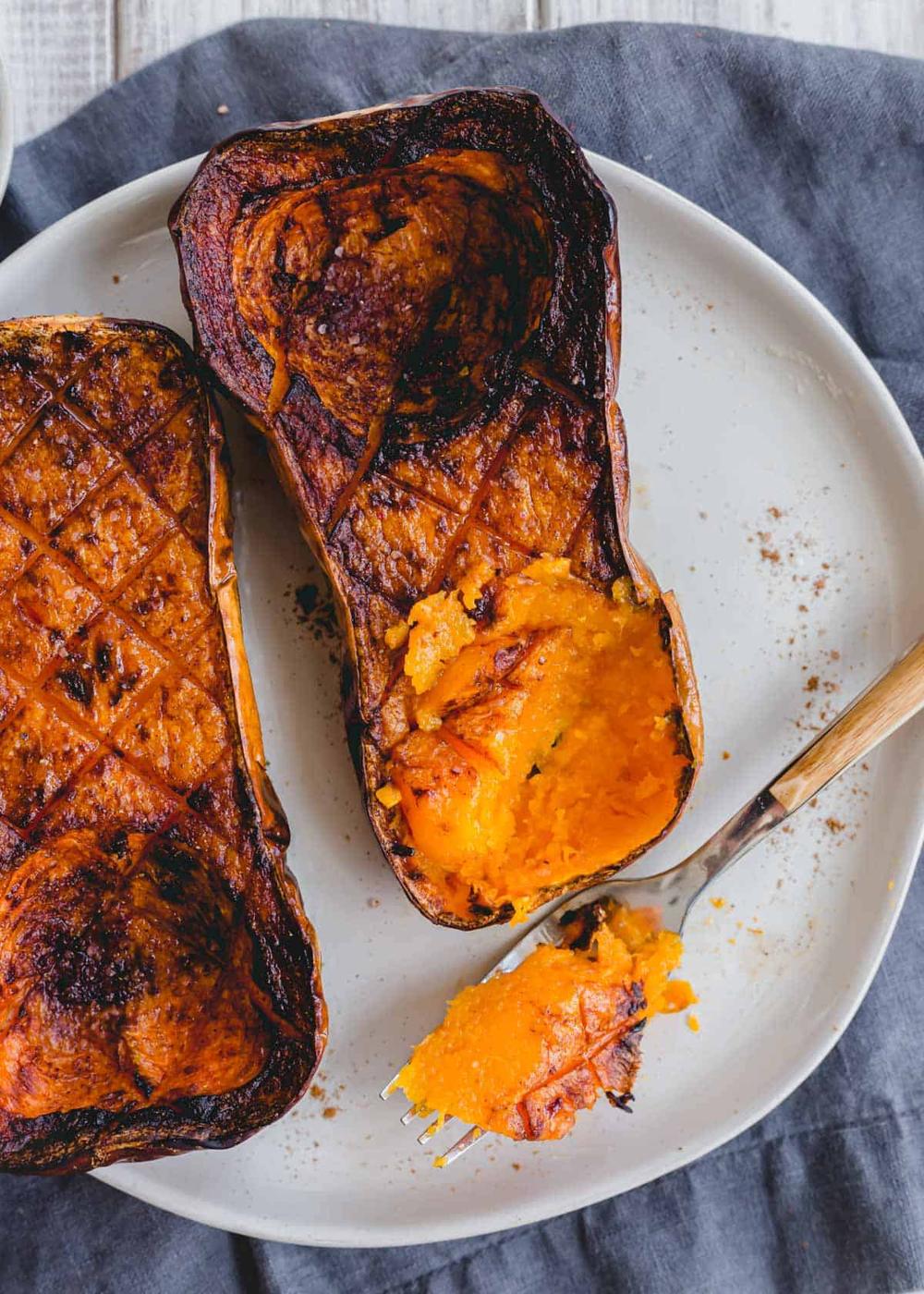 Fork scooping out butternut squash roasted in halves in an air fryer on a plate.