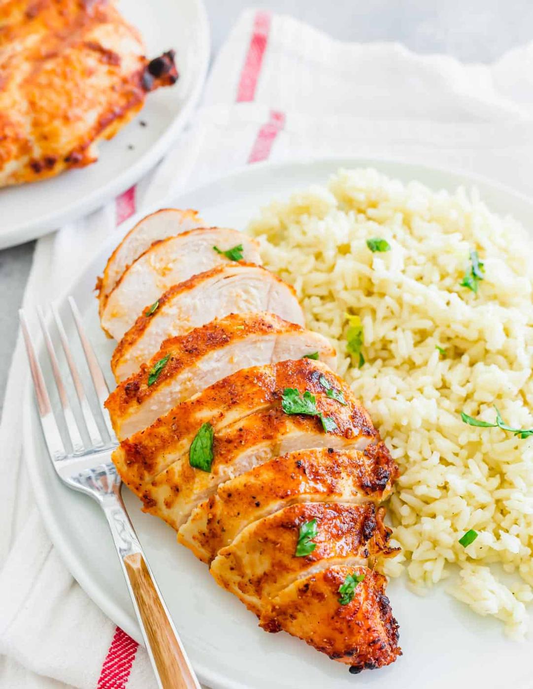 Juicy and tender seasoned frozen chicken breast cooked in an air fryer sliced on a plate with a fork on the side.