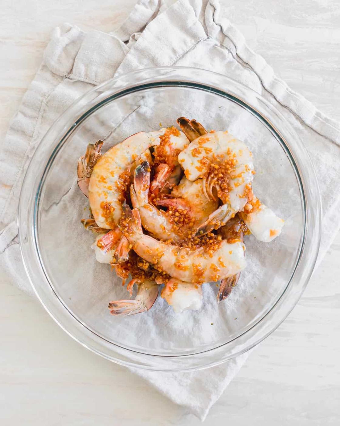 Shrimp marinating in a glass bowl.