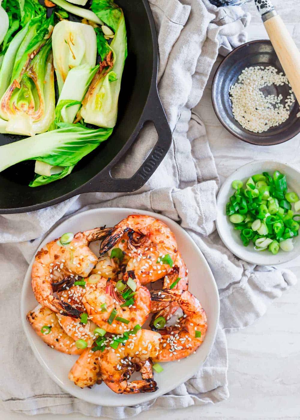 Frozen shrimp made in the air fryer on a plate garnished with green onion and sesame seeds.