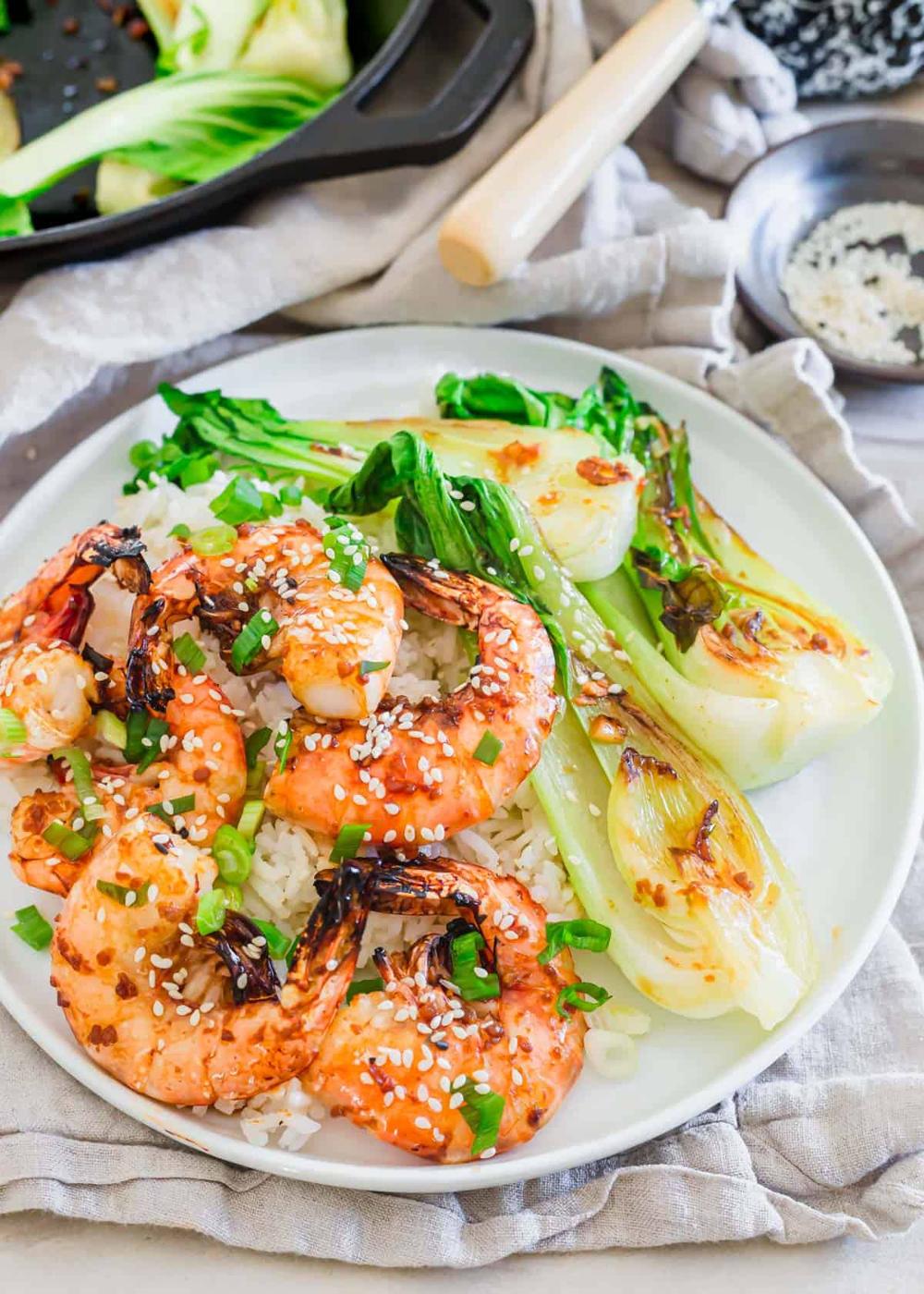 White plate with cooked white rice, sautéed baby bok choy and air fryer frozen shrimp garnished with sesame seeds and chopped green onion.