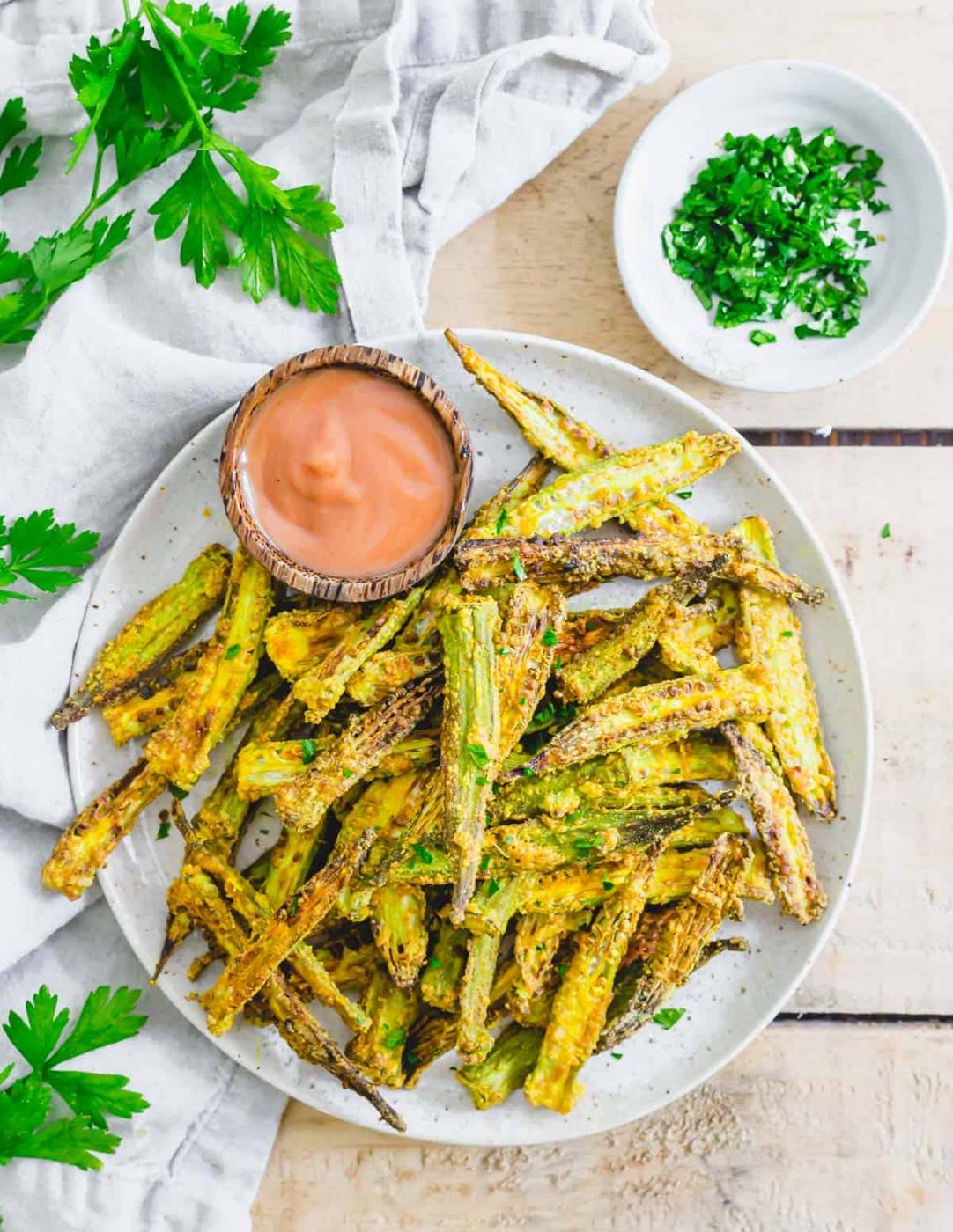 Air fried okra served with a dipping sauce and fresh parsley.