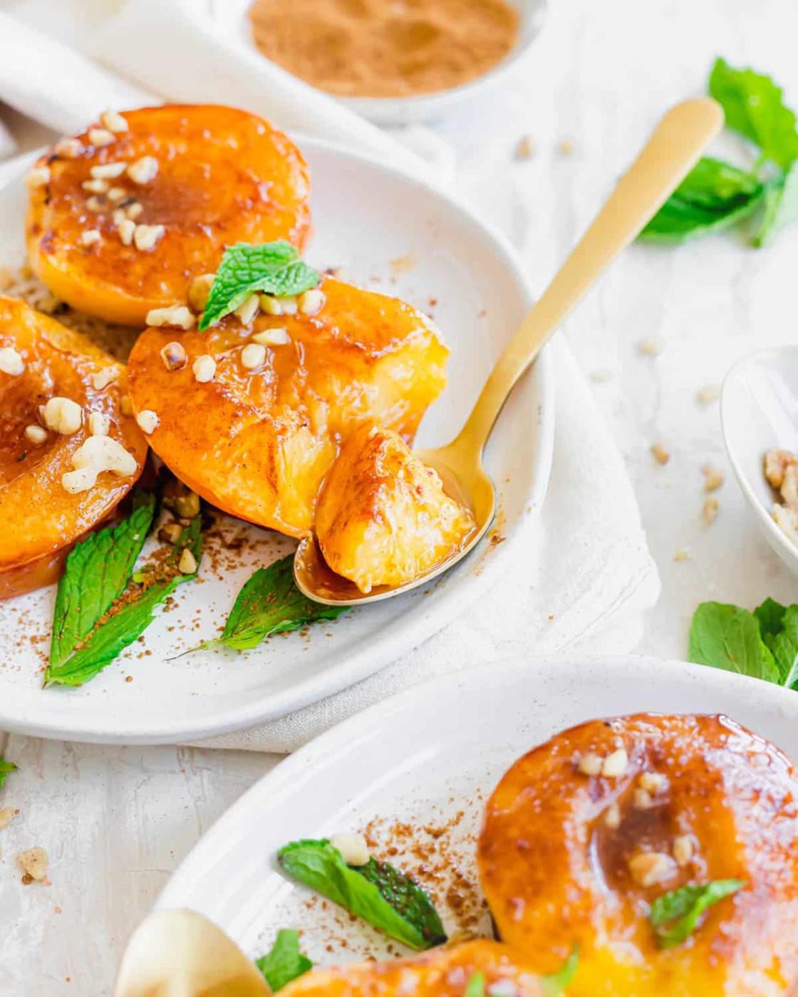 Air fryer peach halves on a plate with a spoon.