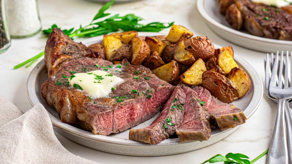 Head on shot of sliced medium-rare air fried ribeye steak with melted butter and parsley.