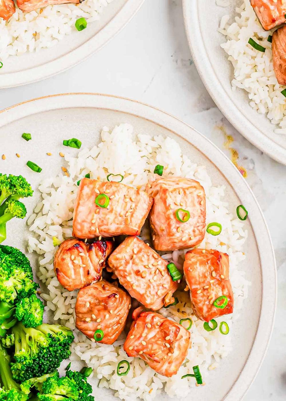 Overhead shot of air fryer salmon bites on a white plate with rice and broccoli.