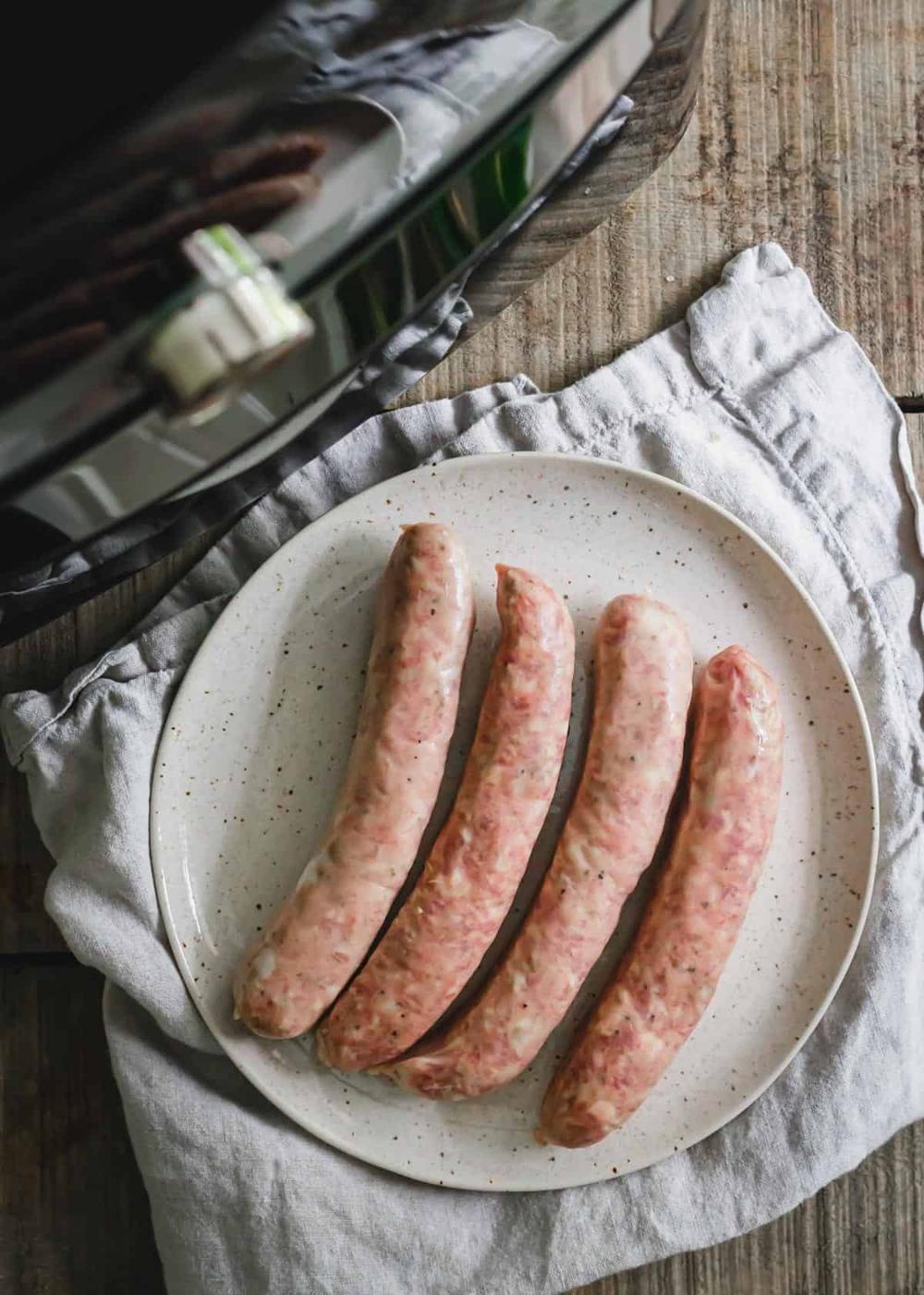 Uncooked pork sausage links on a plate before air frying.