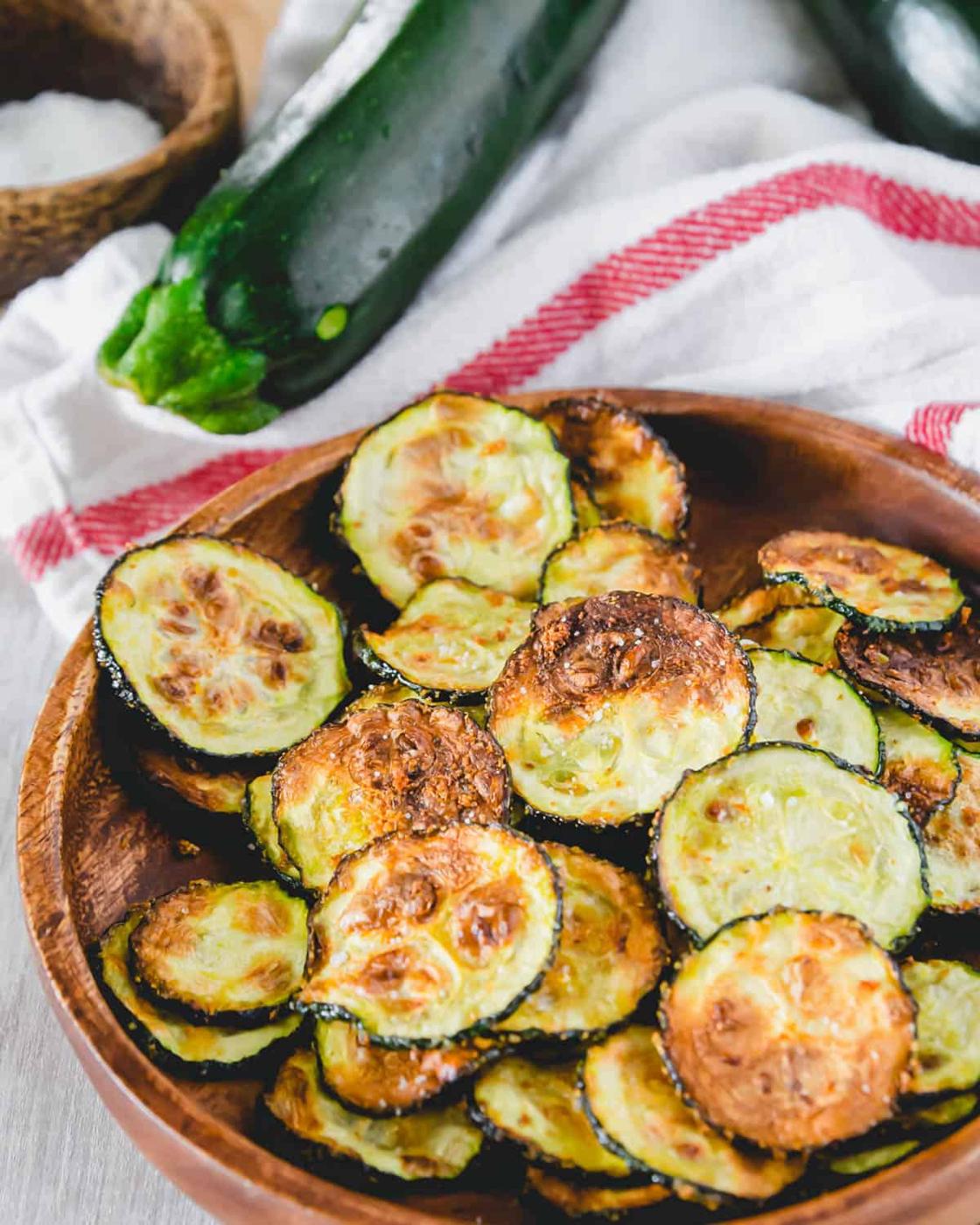 Crispy air fried zucchini chips on a plate seasoned with garlic powder.