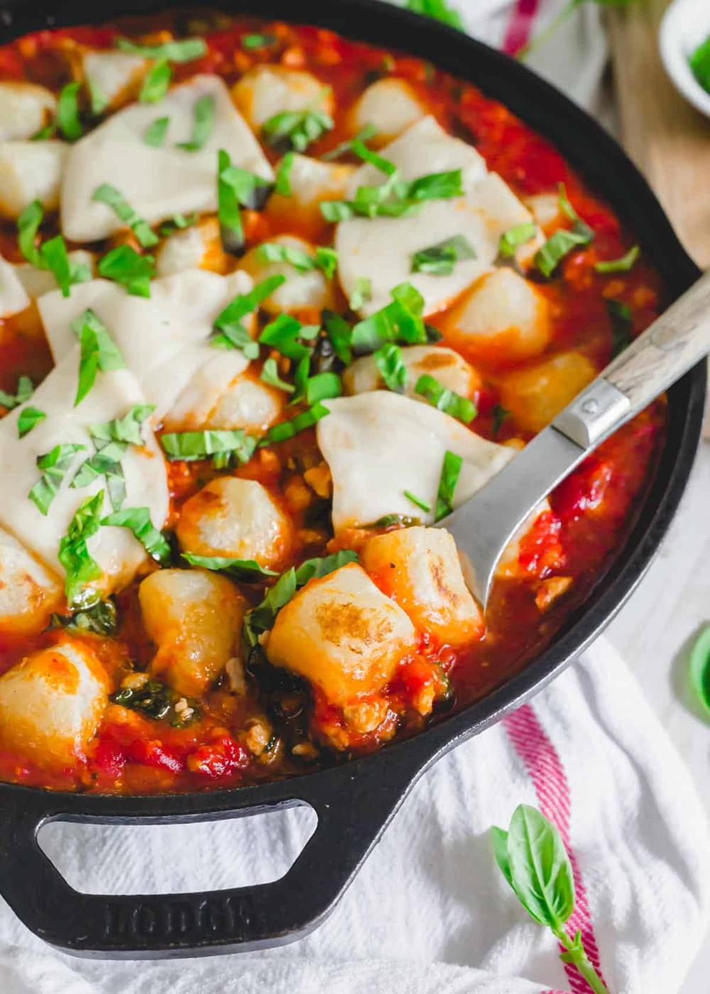 Comforting cauliflower gnocchi skillet with serving spoon.