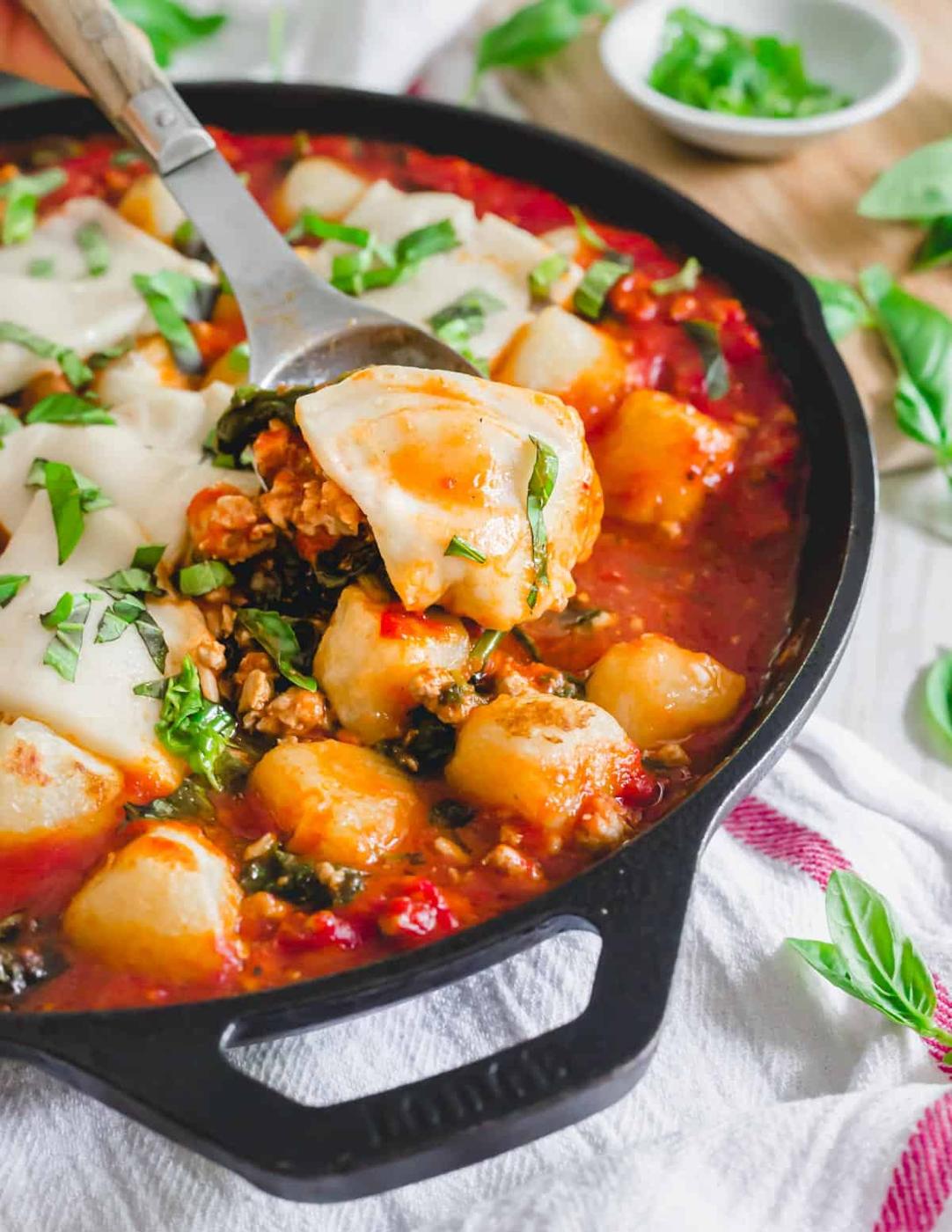 Spoonful of baked cauliflower gnocchi with ground pork, spinach, melted mozzarella cheese and fresh basil.