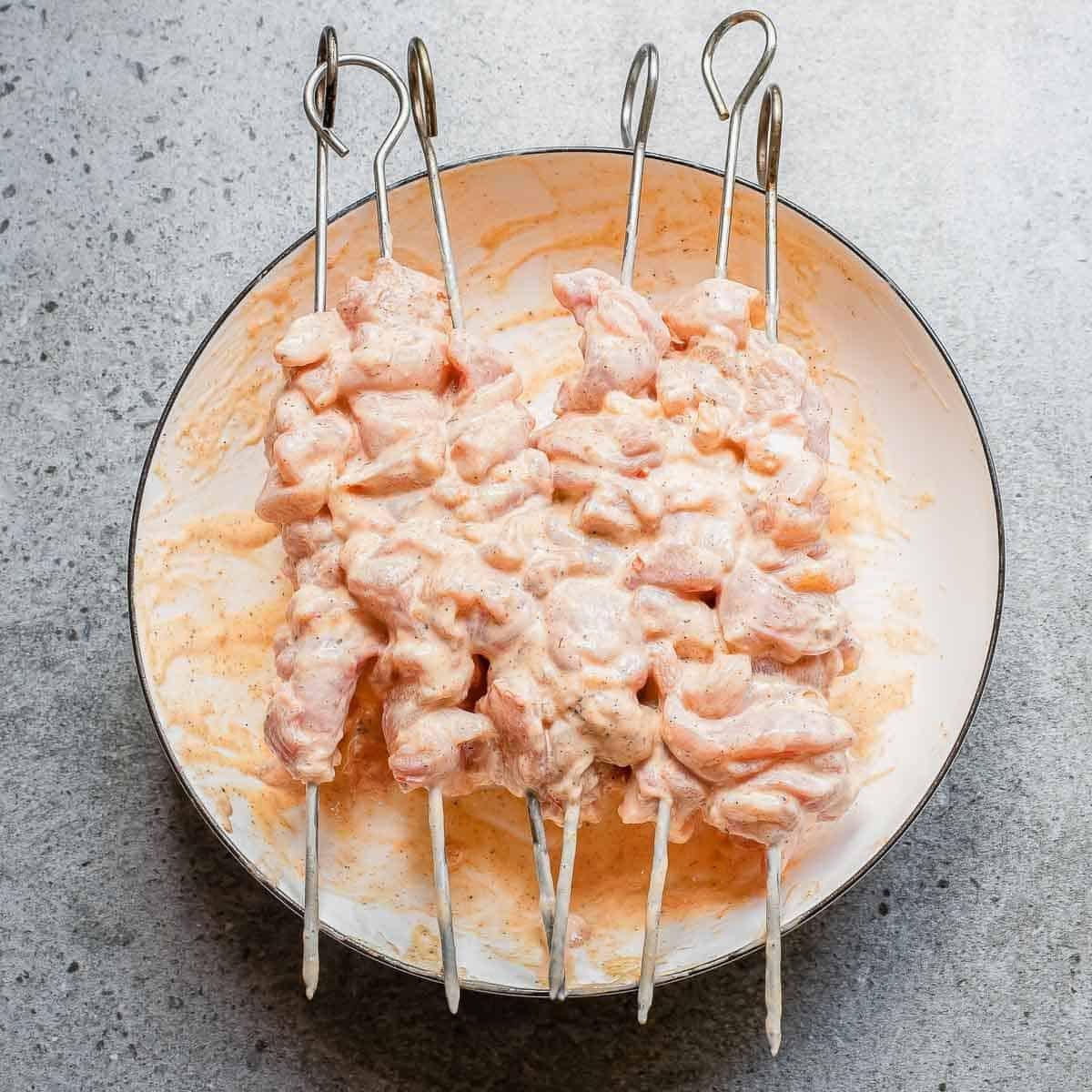 Chicken thigh pieces on metal skewers marinated in a creamy bang bang sauce.