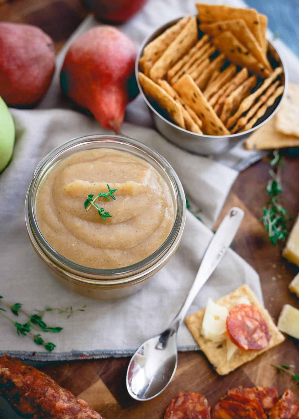 Apple pear butter in a jar garnished with fresh thyme.