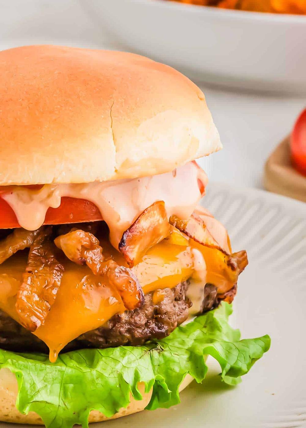 A juicy bison cheeseburger with lettuce, melted cheese, and caramelized onions on a bun, served on a plate with a blurred background.