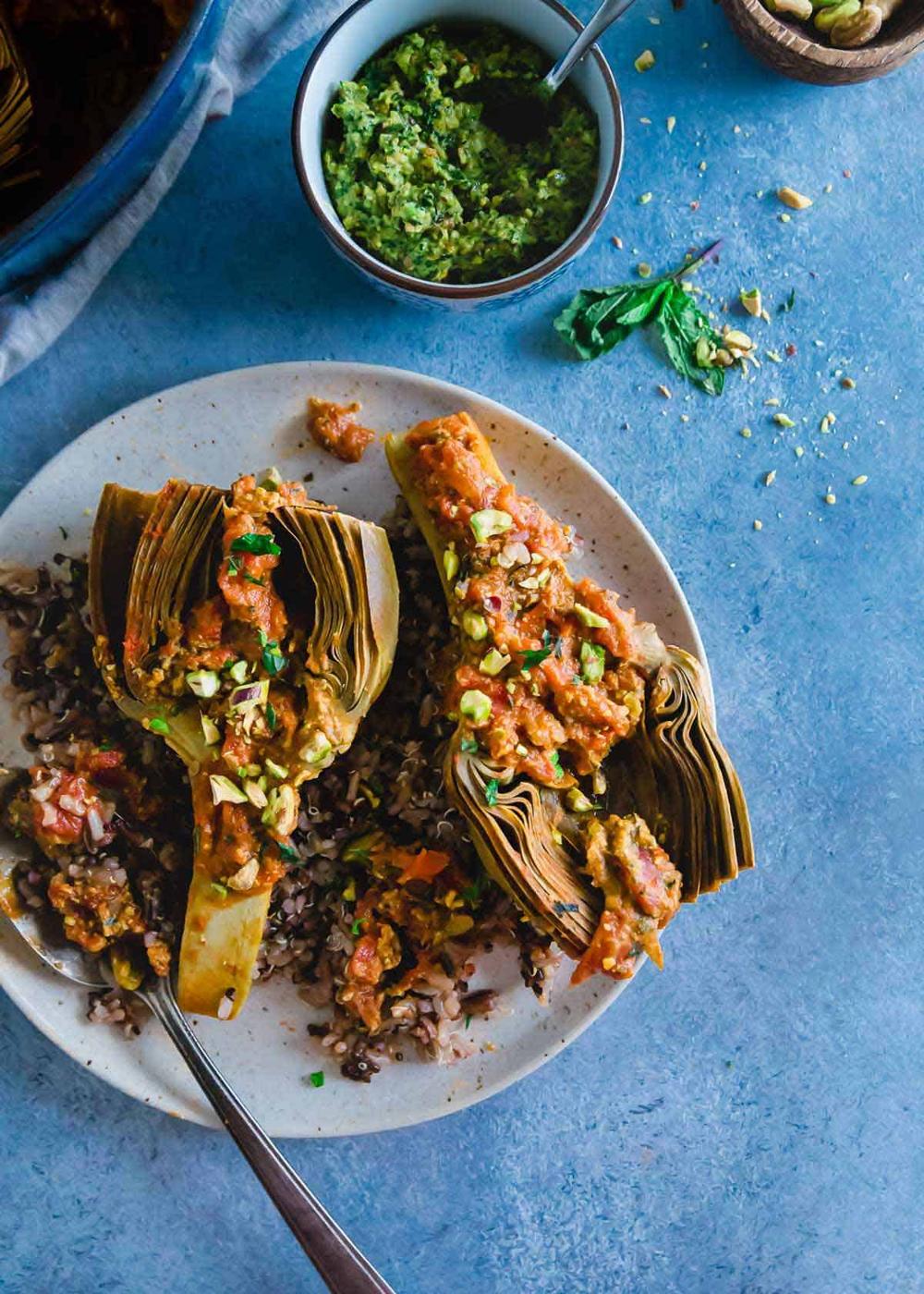An easy recipe for braised artichokes with a chunky white wine tomato sauce and a bright pistachio pesto.