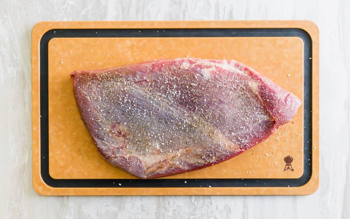 Seasoned veal brisket on a cutting board.