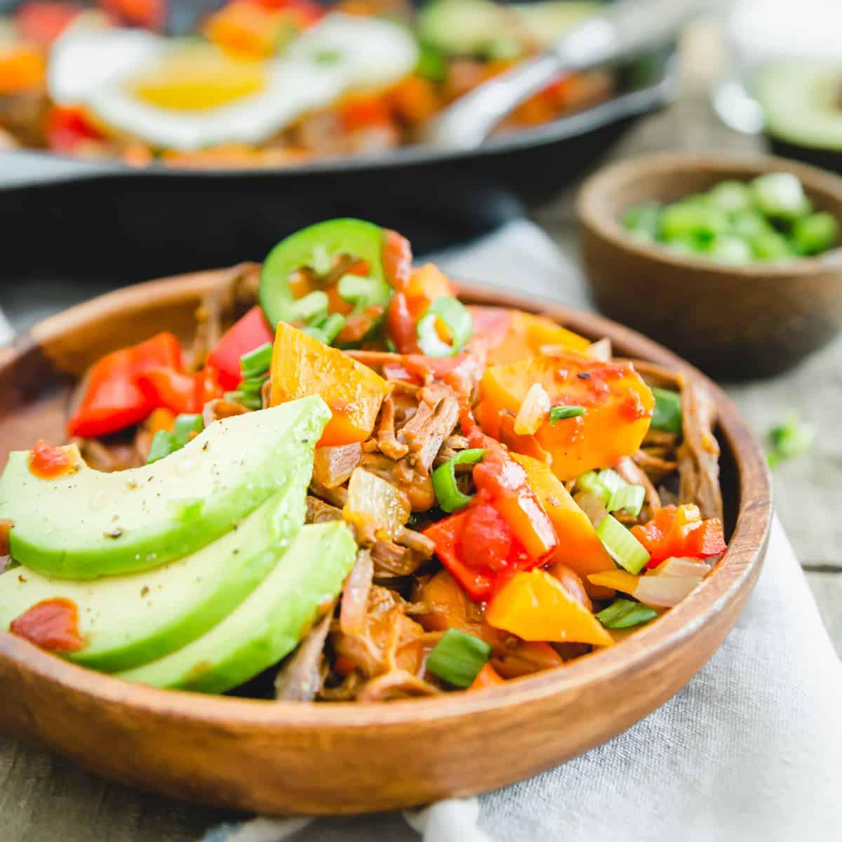 Brisket breakfast hash with sweet potatoes, peppers, beans and sliced avocado for serving.