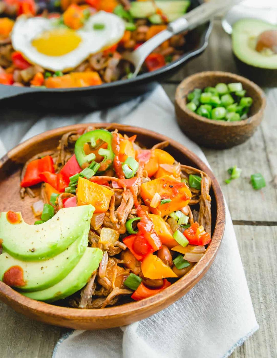 Hearty, smoky beef brisket hash recipe with potatoes, onions, beans and peppers. Topped with a fried egg and BBQ sauce.