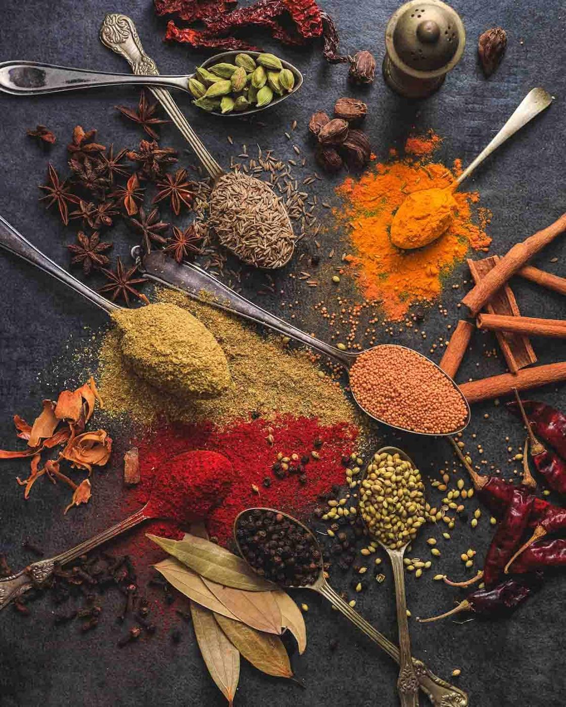 Dried spices on spoons on a dark background.