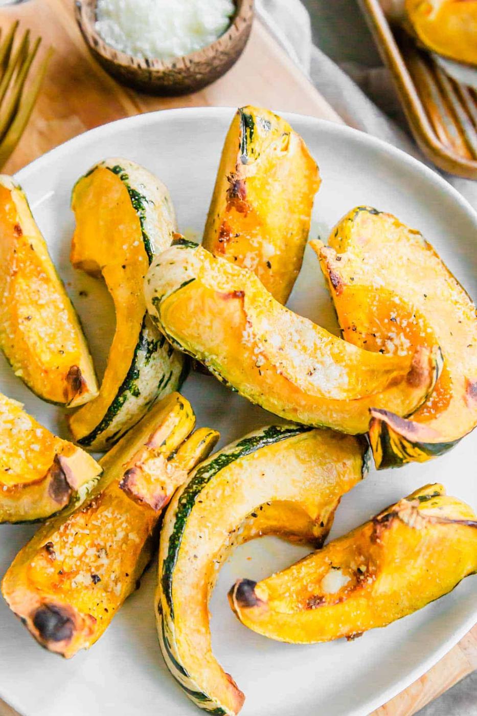 Parmesan carnival squash recipe cut into wedges on a plate.