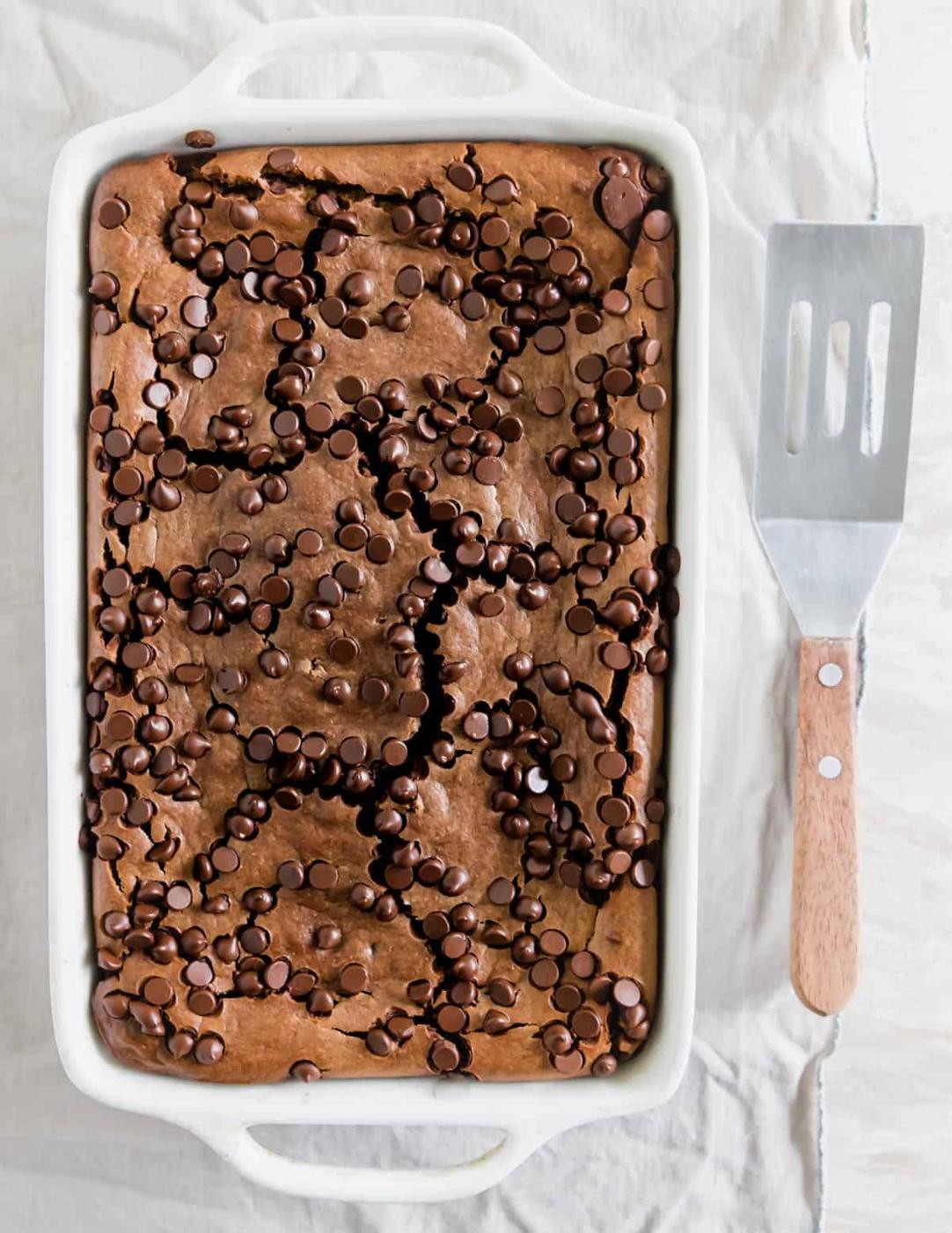 Baked chocolate oats after baking in the oven in a baking dish with a spatula along the side for serving.