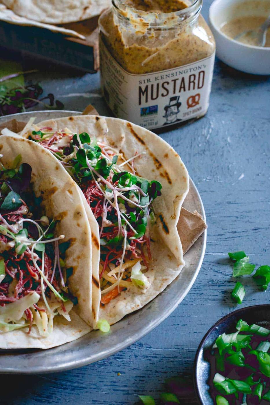 These corned beef tacos are served with a creamy spicy mustard sauce, a simple cabbage carrot slaw and topped with microgreens. Celebrate St. Patrick's Day with a Mexican twist!