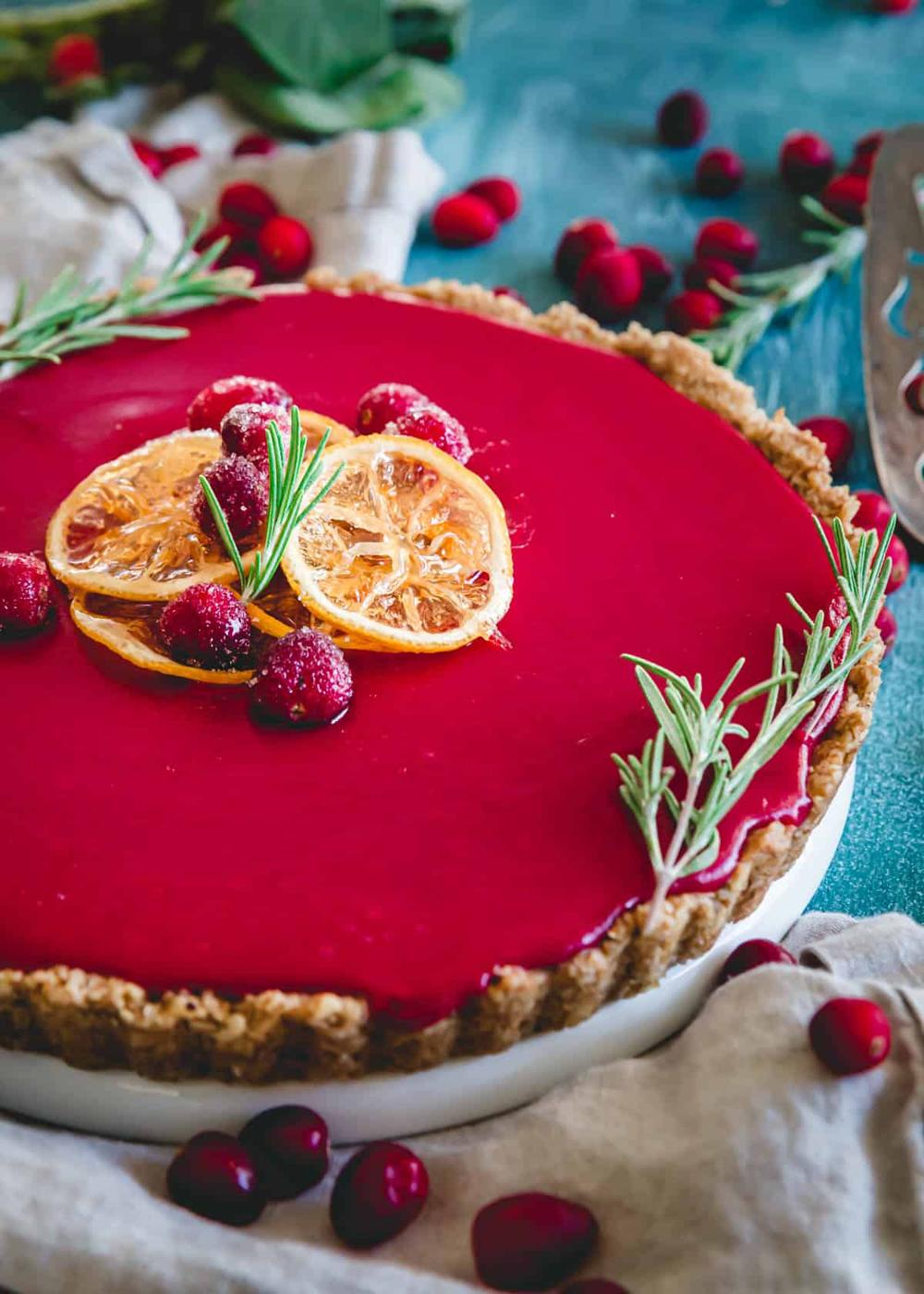Cranberry curd tart garnished with sugared cranberries and candied lemon slices.