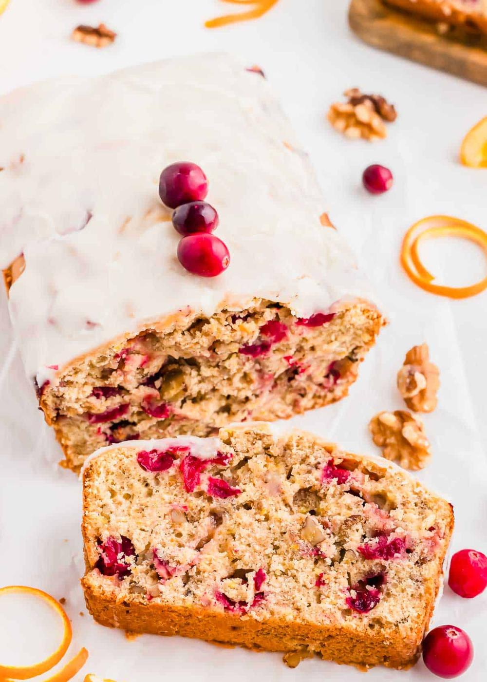 Iced cranberry orange bread loaf with a slice cut.