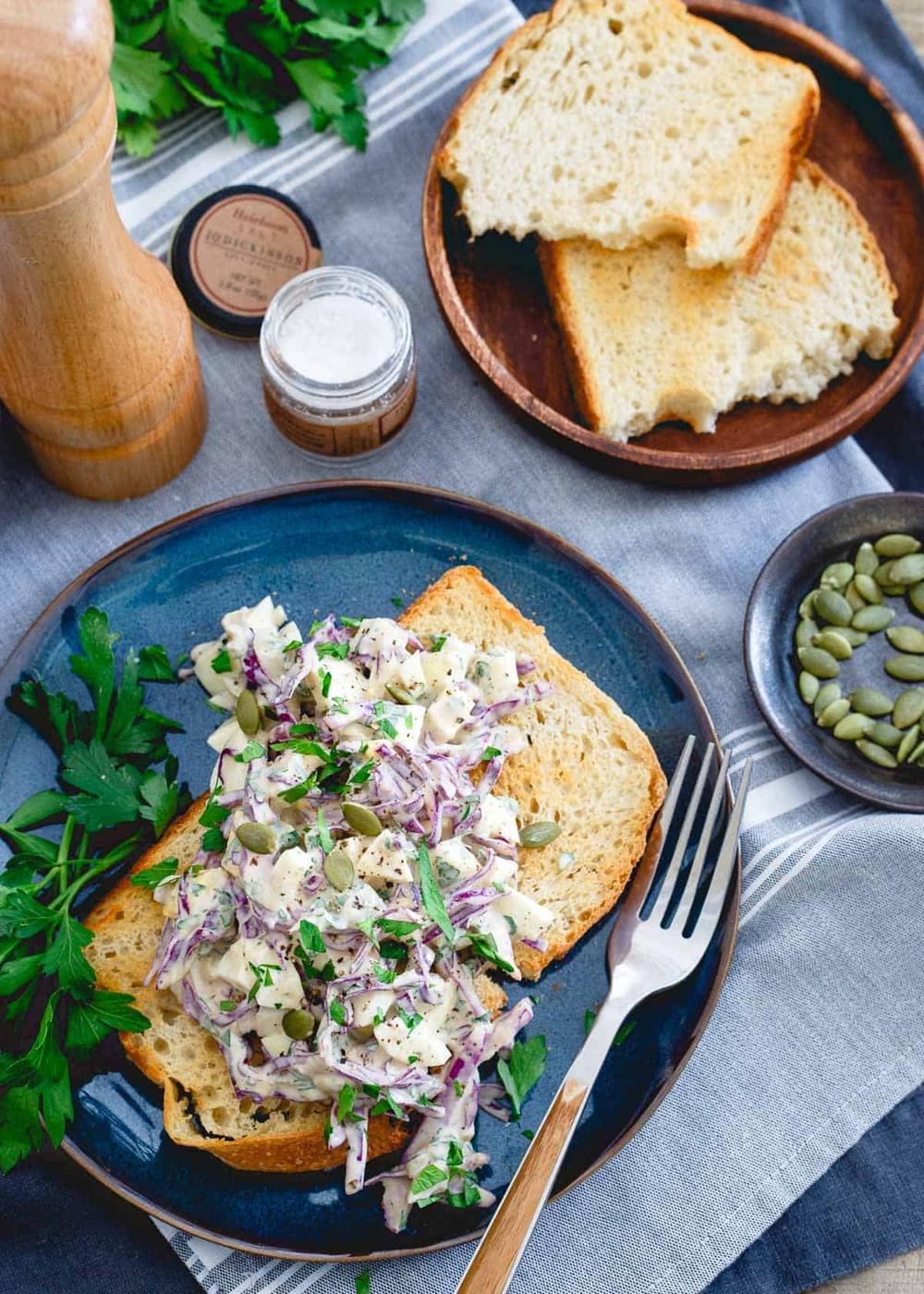 healthy egg salad with greek yogurt on a piece of toasted bread next to a fork