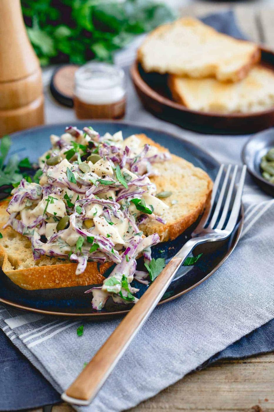 healthy no mayo egg salad on toast on a blue plate next to a fork