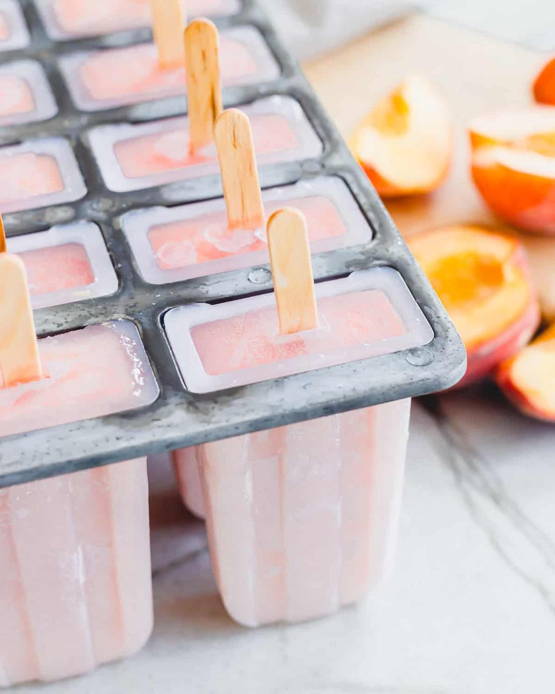 Frozen creamy peach pops in the popsicle mold.