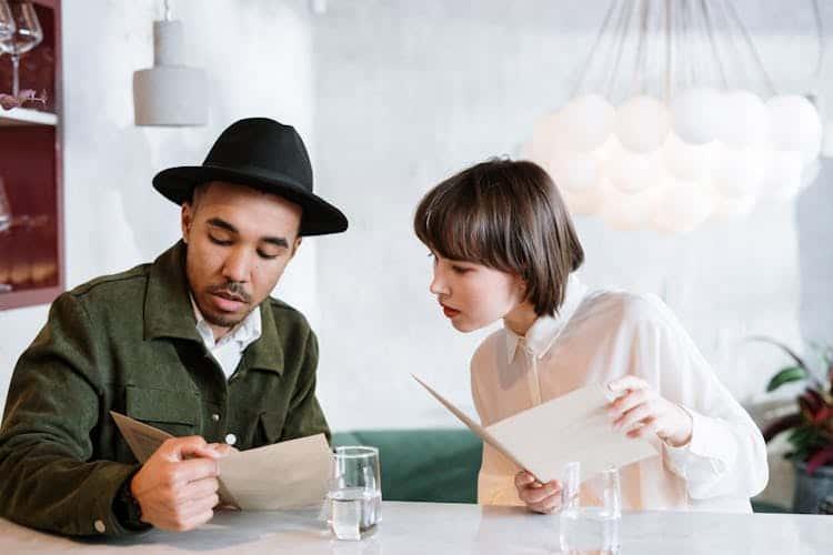 A man and woman are looking at a gluten-free menu at a restaurant.