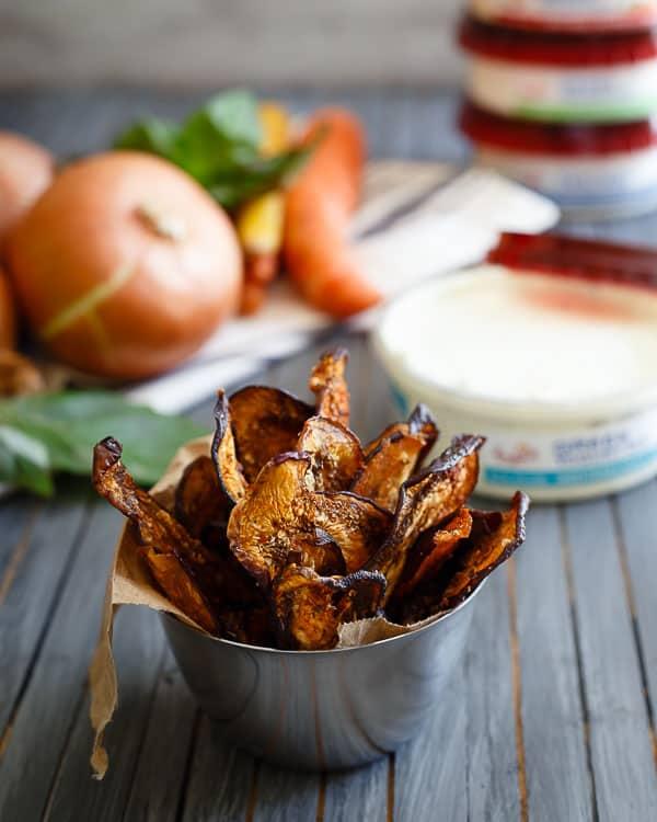 Mediterranean eggplant chips in a small ramekin next to a container of greek yogurt