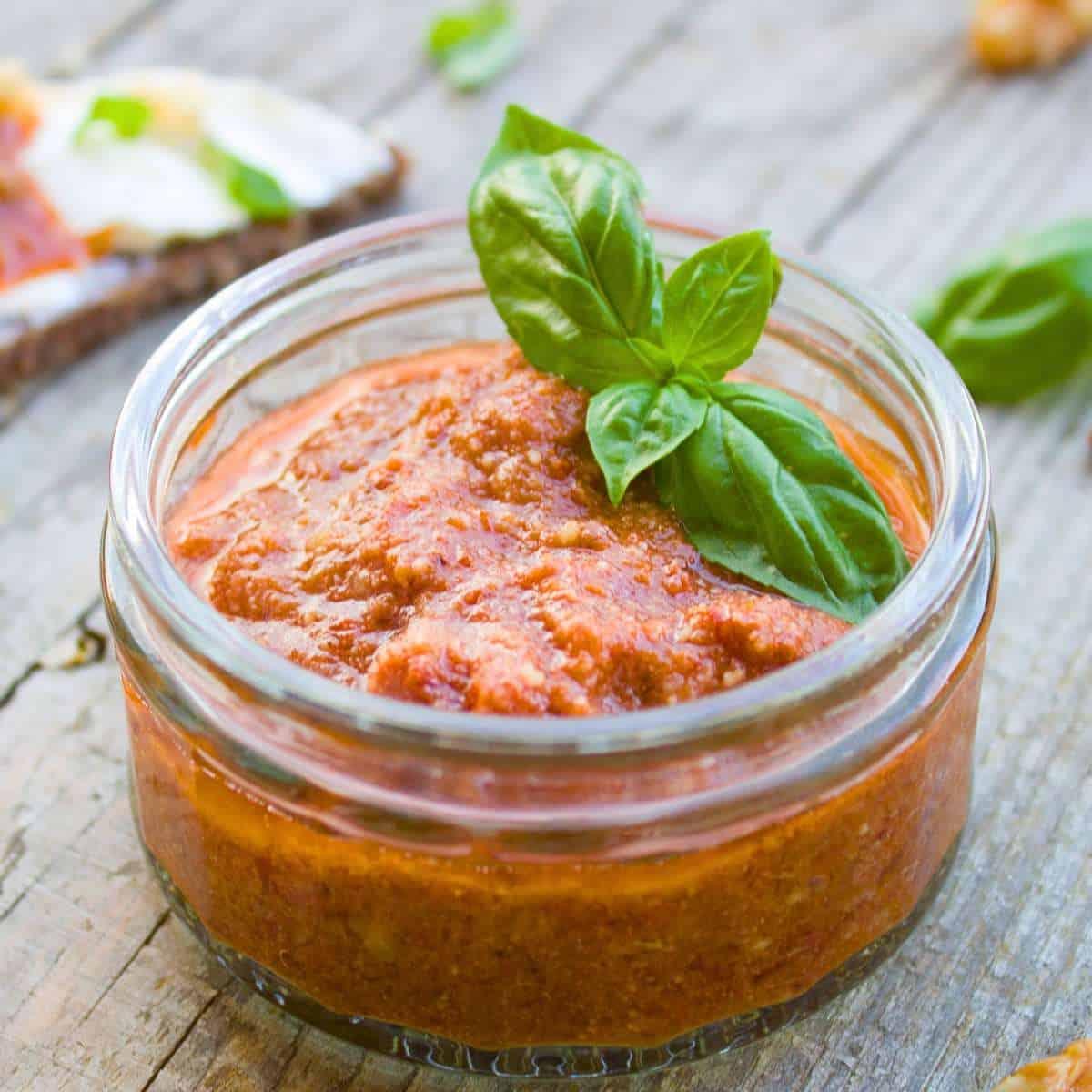 Trapanese pesto in a glass jar with basil leaves.