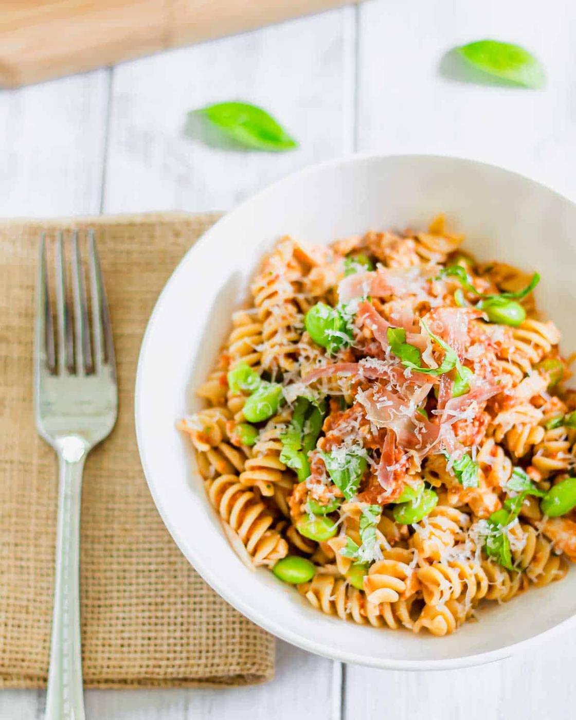 Pesto pasta alla Trapanese in a bowl with crispy prosciutto.