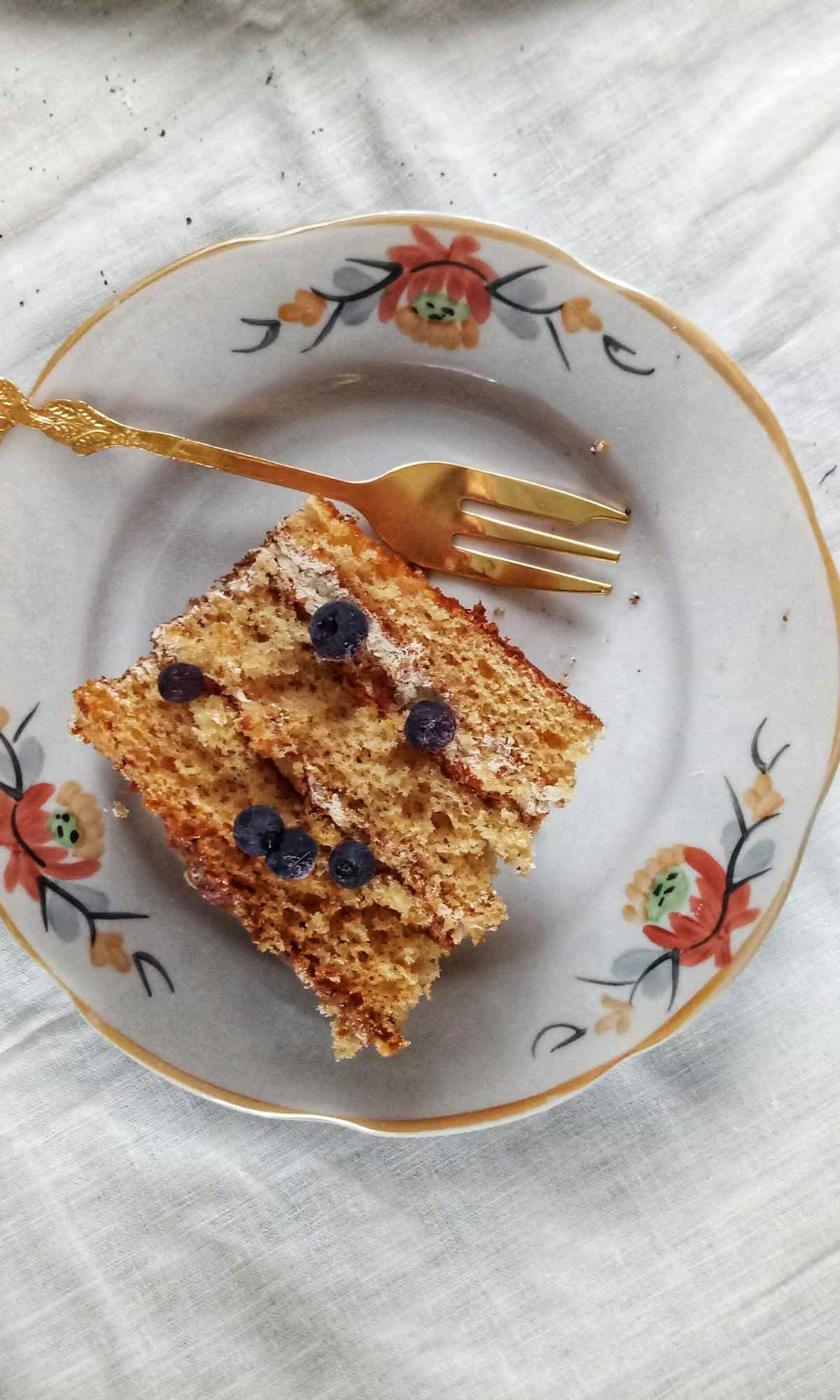 A piece of cake with blueberries on a plate with a fork.