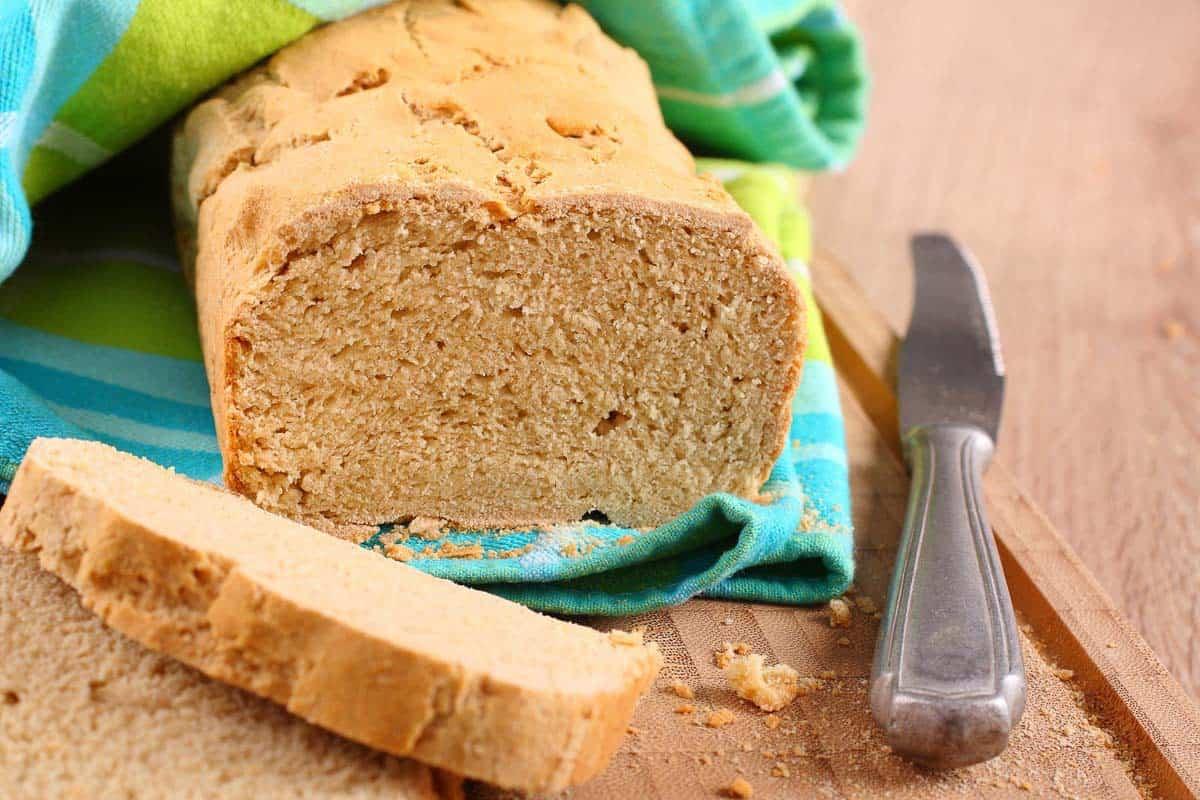 A slice of bread on a cutting board with a knife.