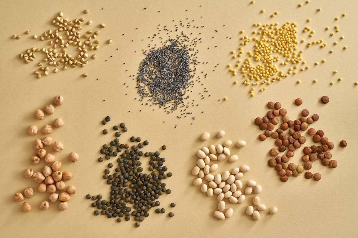 A variety of seeds and legumes on a beige background.