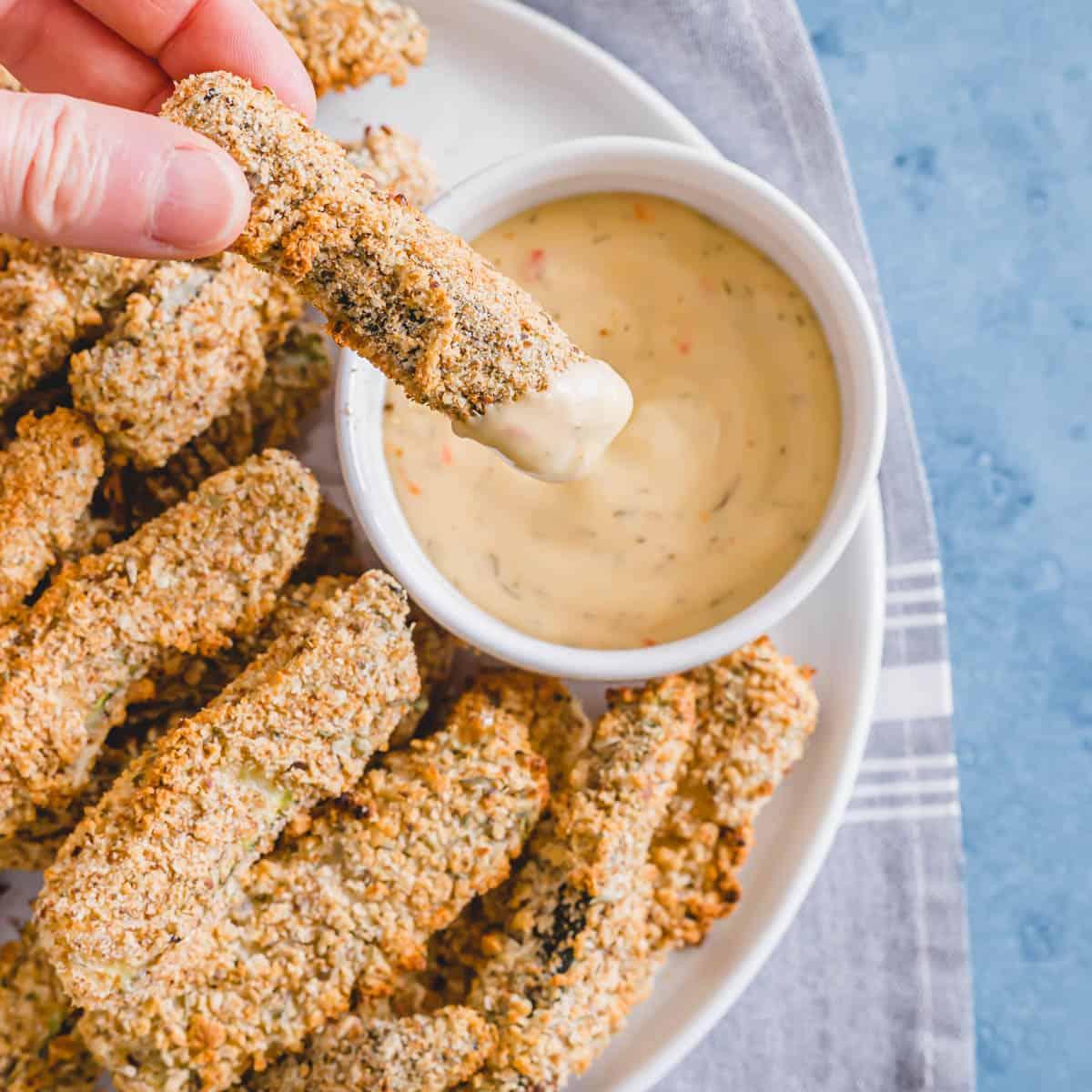 Dipping an oven baked vegan zucchini fry into dipping sauce.