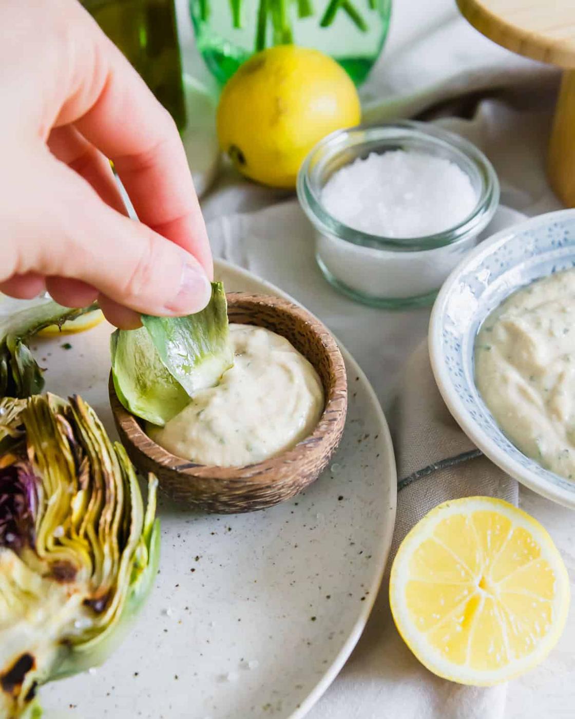 A creamy tahini lemon herb dipping sauce is the perfect accompaniment for grilled artichokes.