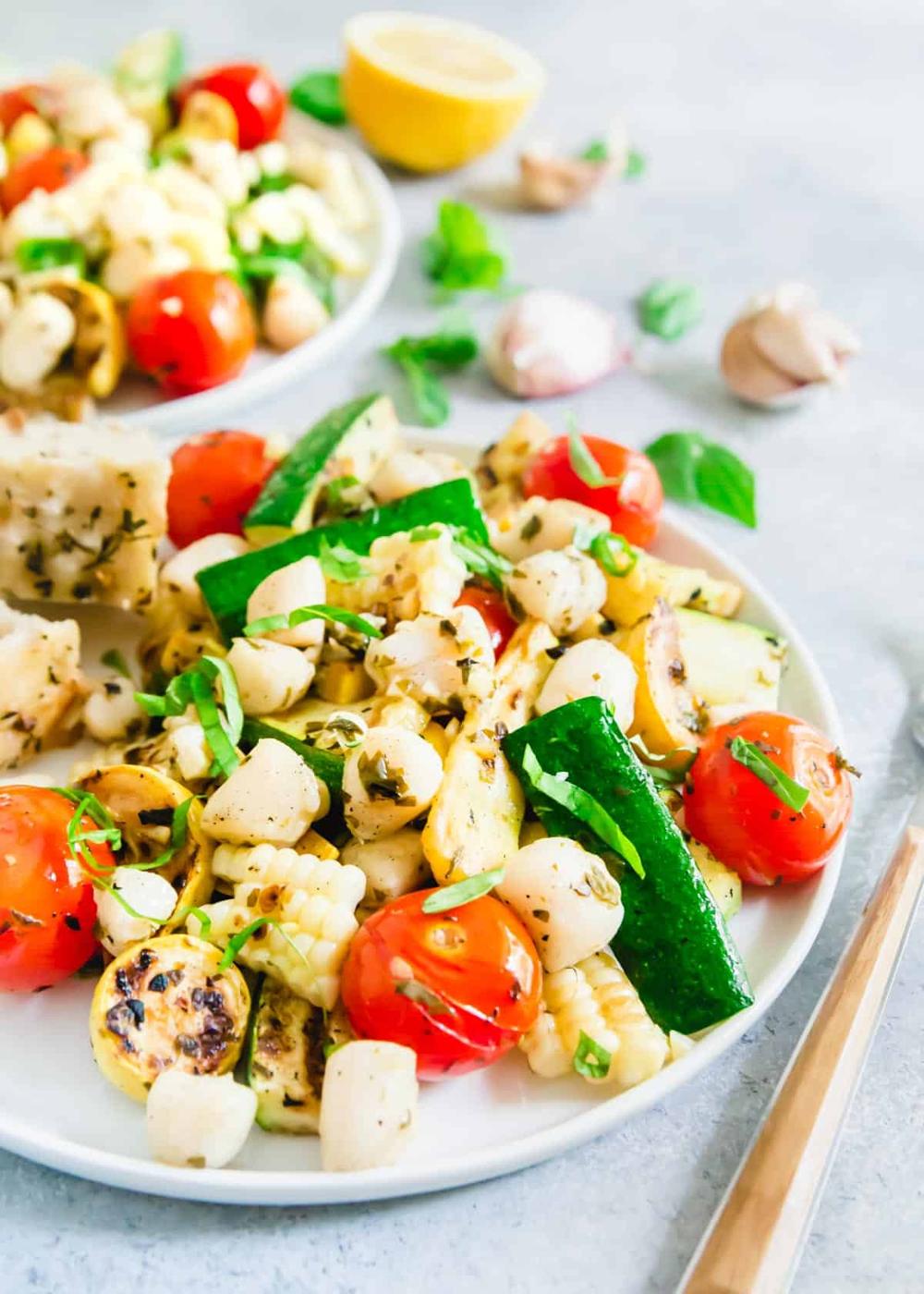 Grilled corn, zucchini, summer squash and tomatoes are tossed in a garlic basil butter sauce and grilled with bay scallops for a light summer meal.
