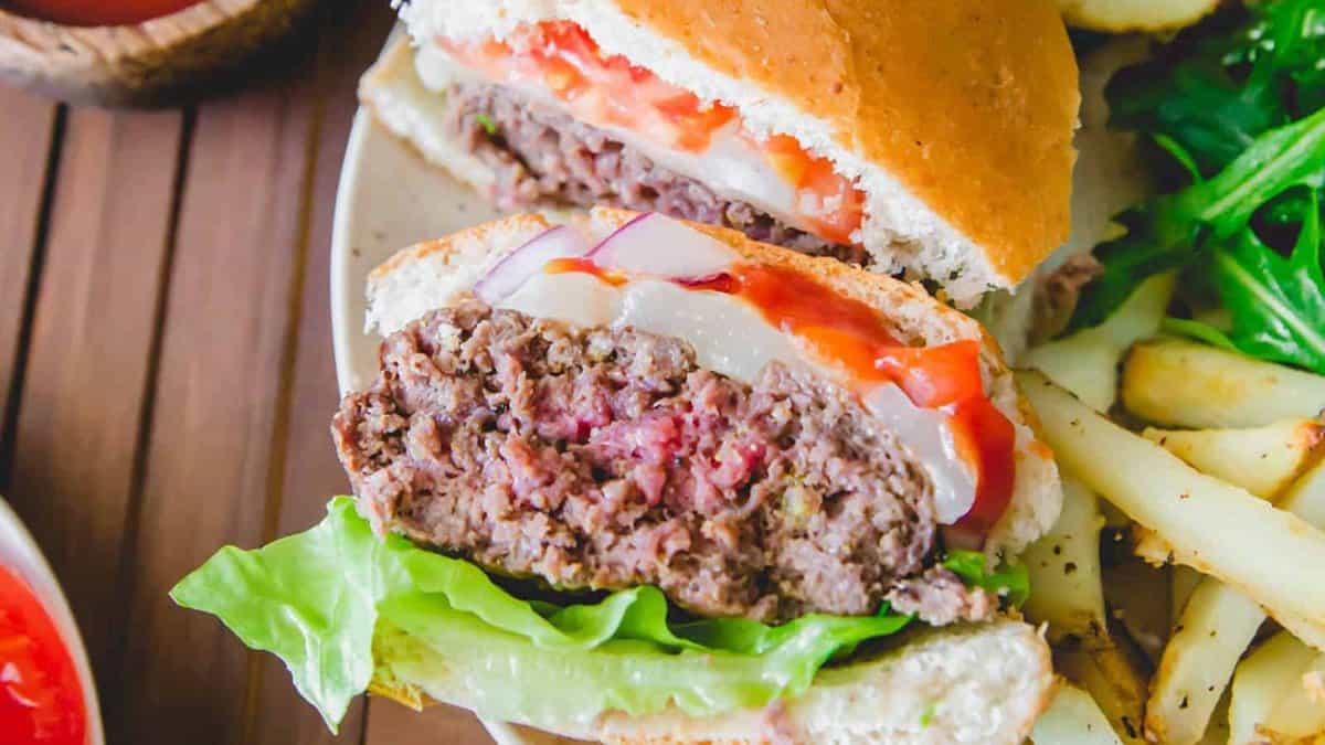 An elk burger with fries and tomatoes on a plate.
