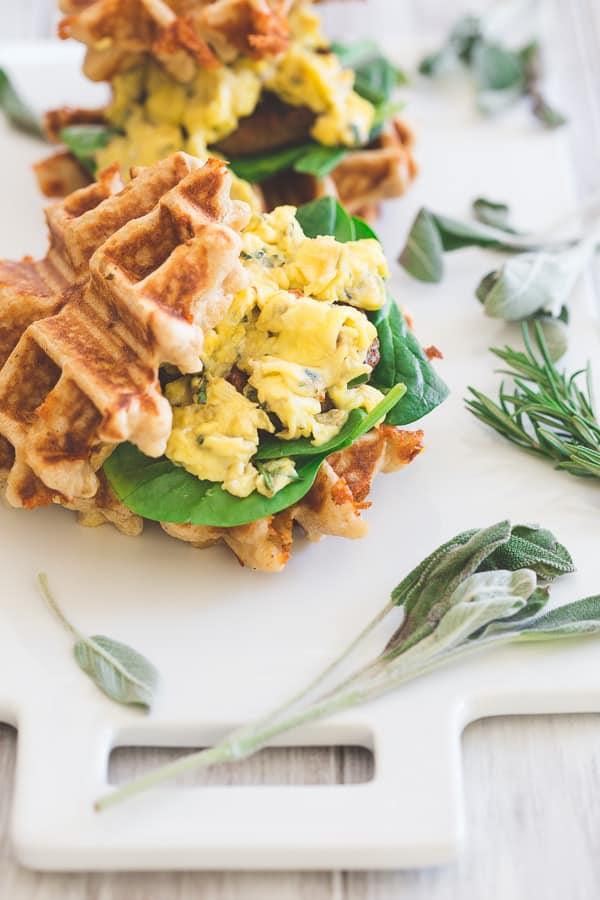 These mini sausage and egg waffle sandwiches are the perfect breakfast or even brinner! Fresh greens, melted cheddar, herbed scrambled eggs and Jones sausage make the perfect bite.