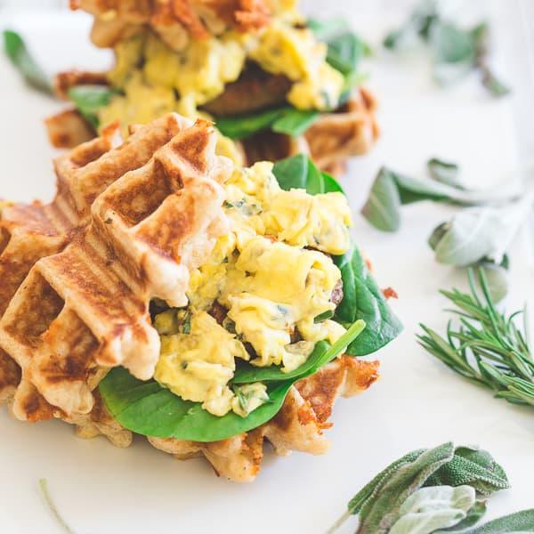 Mini sausage and egg waffle sandwiches are the perfect breakfast or even brinner! Fresh greens, melted cheddar, herbed scrambled eggs and Jones sausage make the perfect bite.