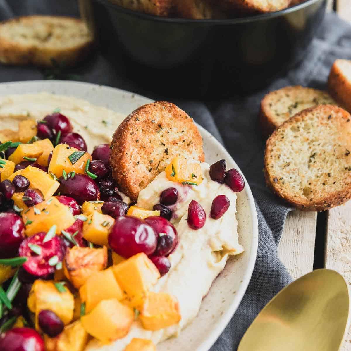 Impress your guests this season with holiday hummus featuring butternut squash, cranberries and pomegranates.