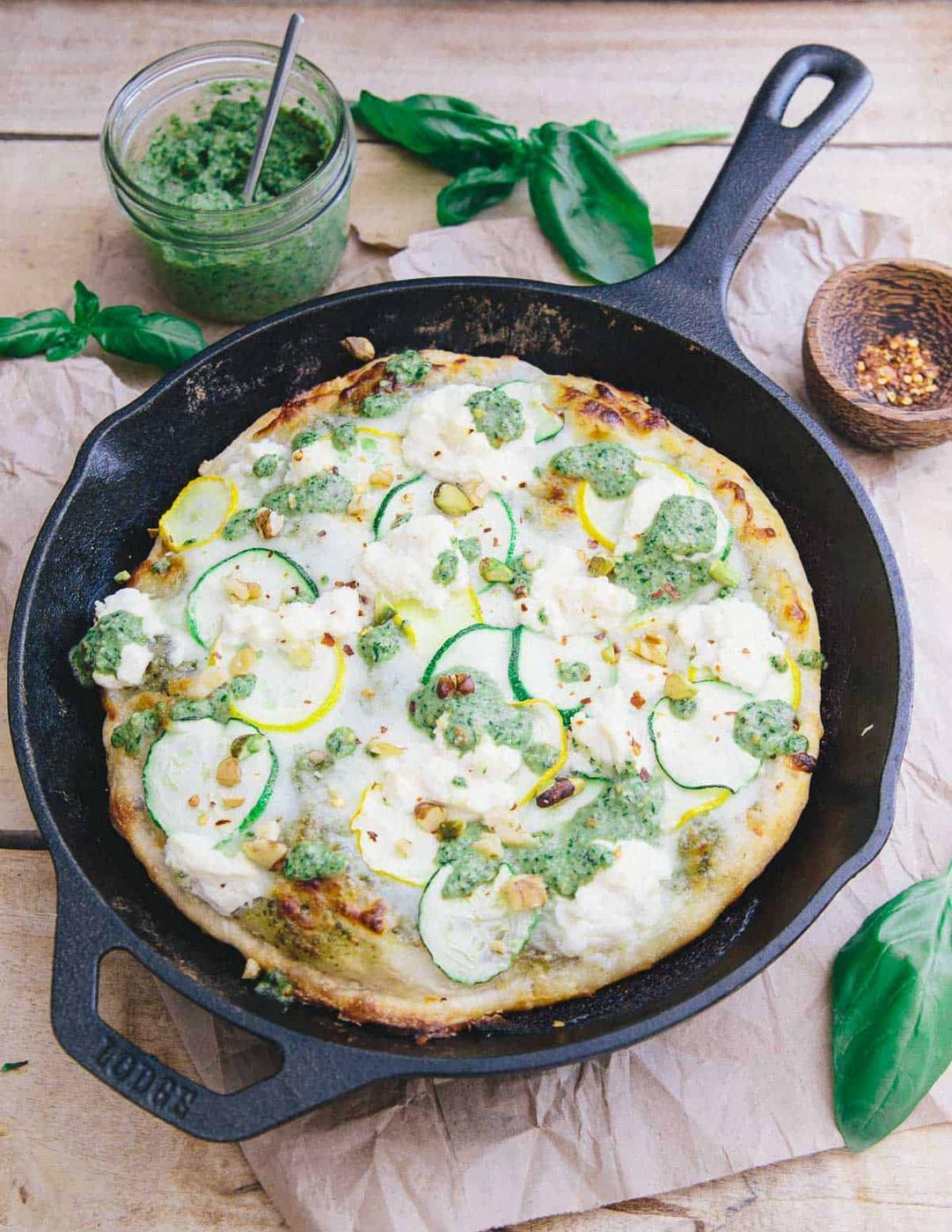 Zucchini pesto pizza in a cast iron skillet.