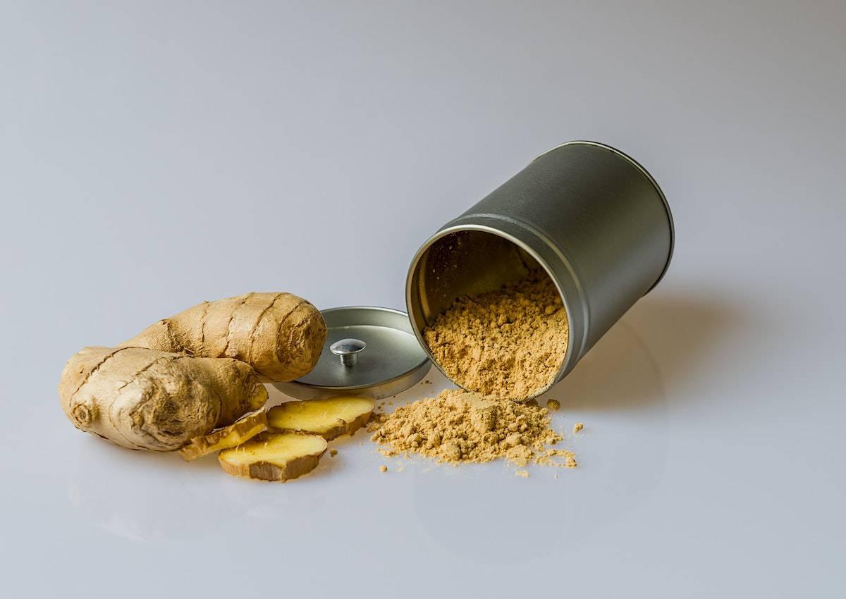 Fresh ginger sliced next to a tin with ground ginger.